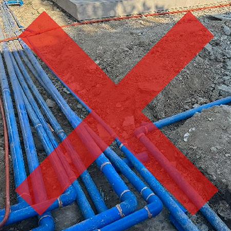 A network of blue underground swimming pool pipes lying in a dirt trench with a large red X over them, symbolizing the avoidance of messy and expensive plumbing demolition.